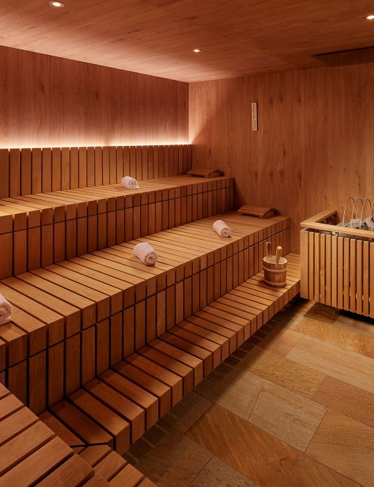 Sauna spacieux avec des serviettes roulées placées sur les sièges.