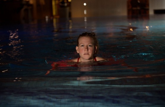 A woman swims in a pool with light illumination.