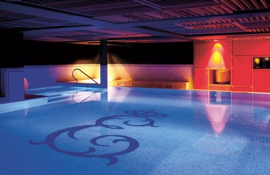 Pool with the Hotel Erbprinz emblem in atmospheric lighting.