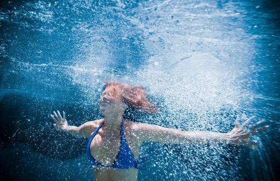 A woman dives under water.